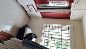 Una stanza con un letto, una finestra con inferriate, un soffitto rosso e bianco e un pavimento piastrellato.