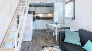 Un espace de vie compact comprenant une chambre en mezzanine, une kitchenette et un coin repas.