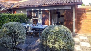 Une maison avec un patio, une table et des chaises, et une clôture en bois.