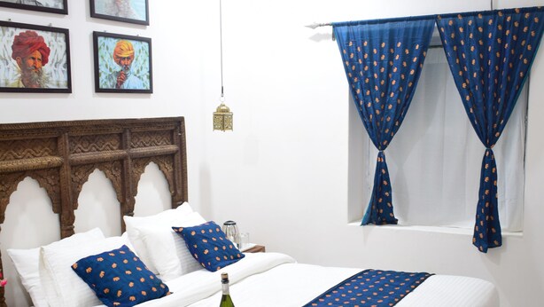 Une chambre à coucher bien rangée, avec un lit, des oreillers, une table de chevet et des rideaux.