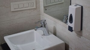 Une salle de bain avec un lavabo blanc, un miroir et un distributeur de savon.
