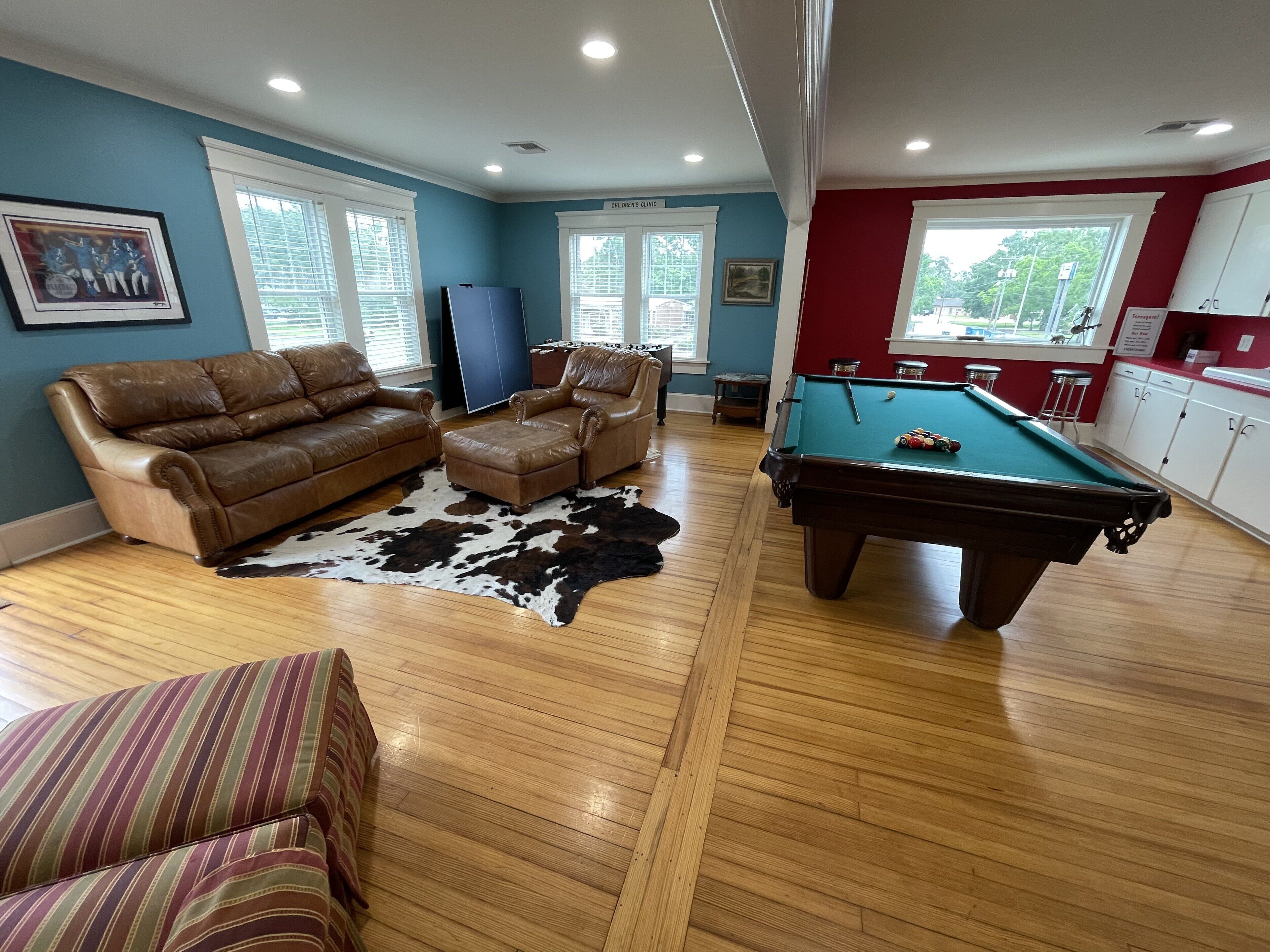 A living room with a pool table, leather sofas, and a cowhide rug.