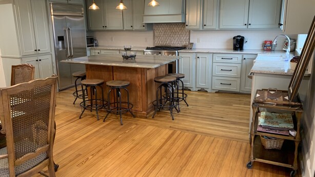A kitchen with a central island, bar stools, wooden chairs, and a cart with baskets. - Park Avenue Loft overlooking Parkerson Avenue (Crowley)