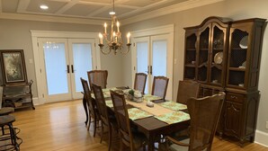 A dining room with a wooden table, chairs, a chandelier, and a china cabinet. - Park Avenue Loft overlooking Parkerson Avenue (Crowley)