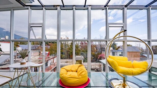 Et moderne interiør med et glastilbordsbords, en gul beanbag-stol og en hængestol med gule puder.