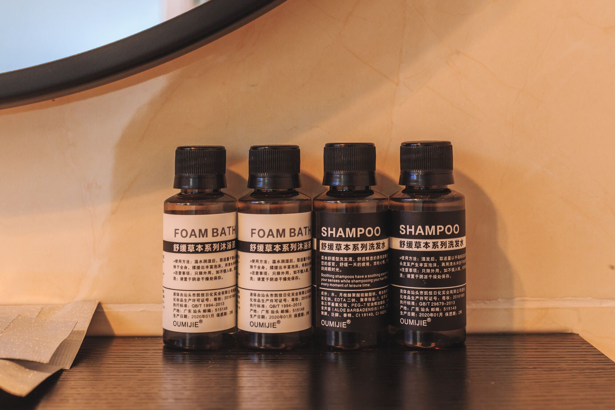 Four bottles of OUMIJIE products on a wooden surface.