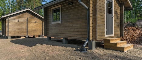 Two wooden cabins with a gravel driveway, surrounded by trees.