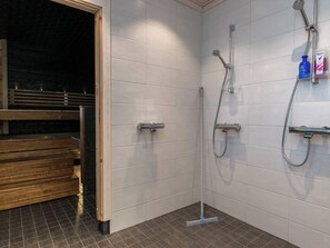 A shower area with a tiled wall, a wooden bench, and a shower head.