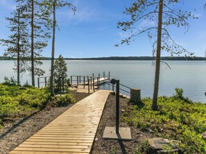 A wooden dock leading to a calm lake with a clear sky.