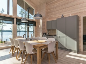 Een moderne keuken met een houten inrichting, een eethoek met een tafel en stoelen, en uitzicht op een meer.