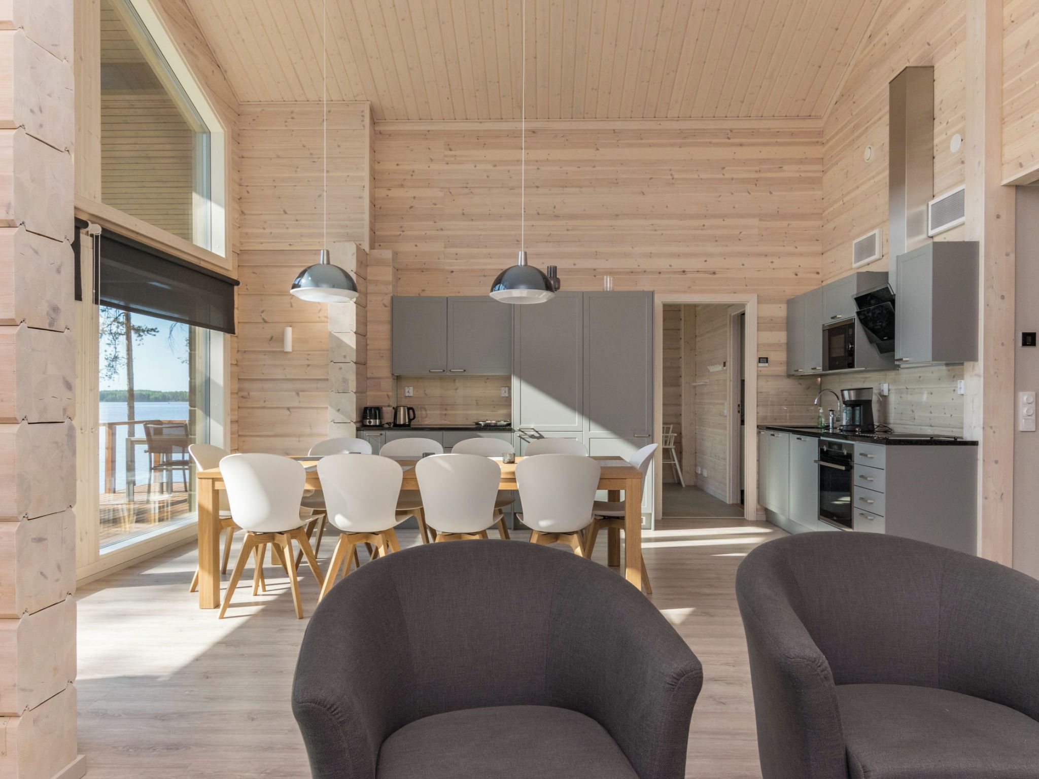 Ein modernes Interieur mit Essbereich, Küche und großen Fenstern.