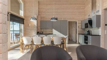 Ein modernes Interieur mit Essbereich, Küche und großen Fenstern.