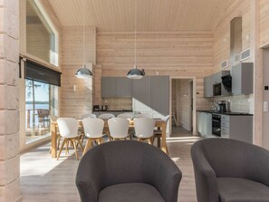 A modern interior with a dining area, kitchen, and large windows.