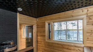 Una cabaña con paredes de madera y una ventana con vistas a un lago.