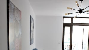 Una sala de estar moderna con una mesa de comedor de vidrio, un sofá azul y un ventilador de techo.