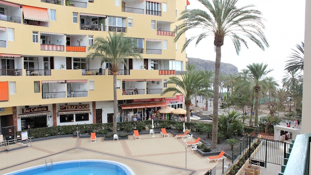 Un hotel con varios balcones, piscina y zonas de estar al aire libre.