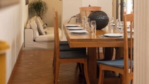 Un coin repas avec une table en bois dressée pour quatre personnes, un lustre et un objet décoratif blanc placé au-dessus de la table.