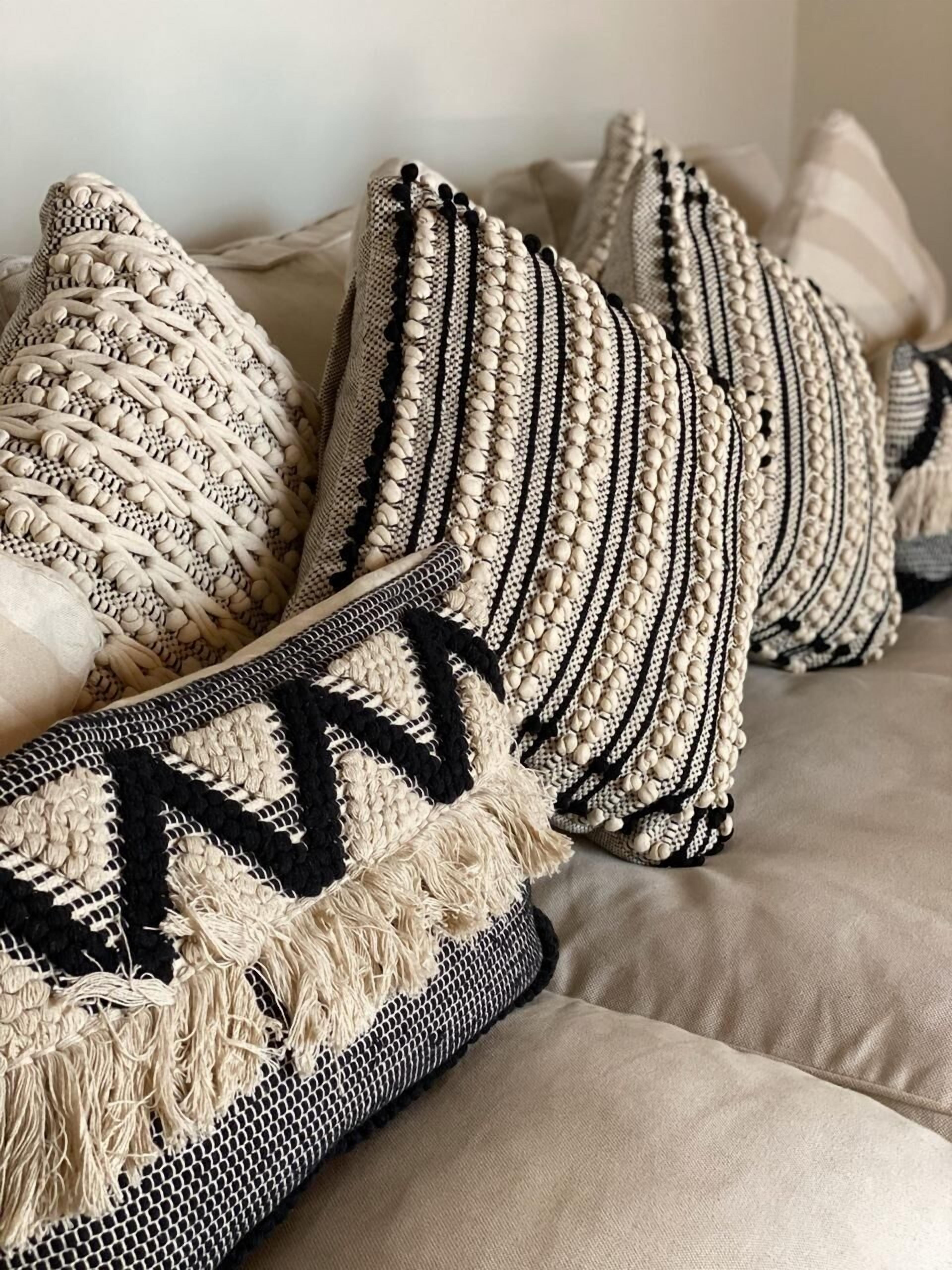A bed with multiple pillows featuring intricate woven patterns and tassels.