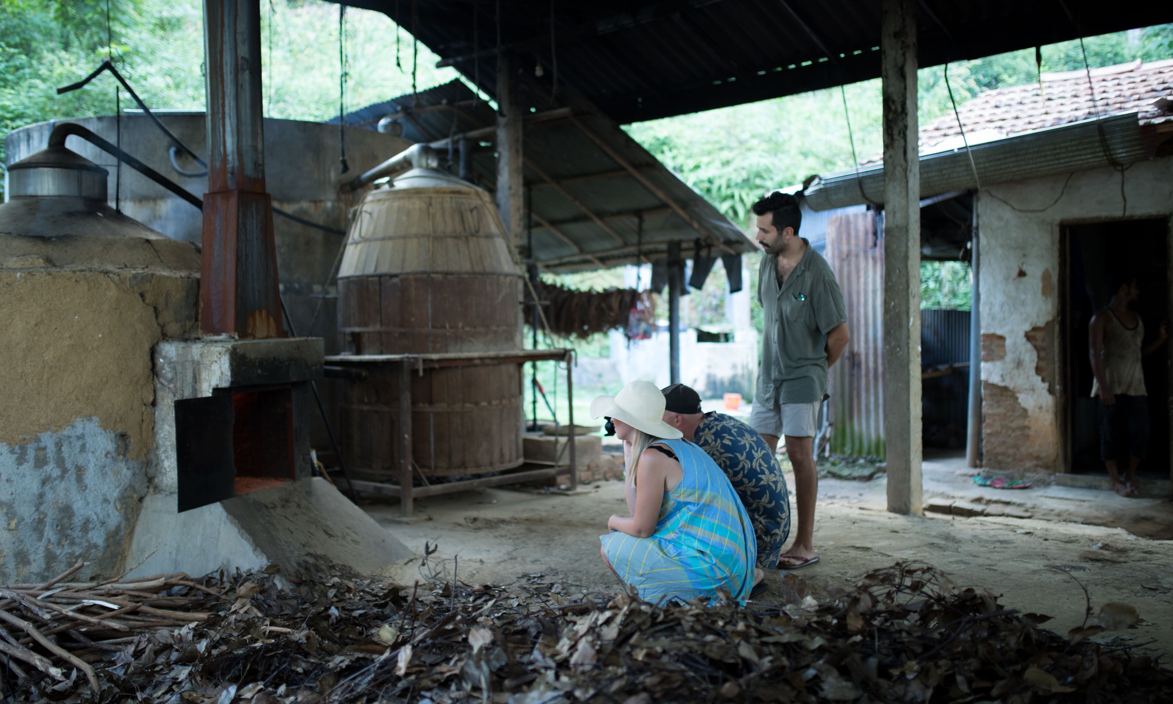 Un décor extérieur rustique comprenant un grand réservoir d’eau, une structure en béton et une personne assise par terre.