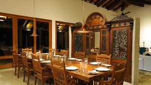 A dining area with a wooden table set for a meal, surrounded by chairs, and a decorative mirror above the table. - Makuludola Bungalow (Malimbada)