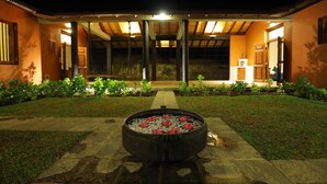 A courtyard with a fire pit in the center, surrounded by a pathway and greenery. - Makuludola Bungalow (Malimbada)