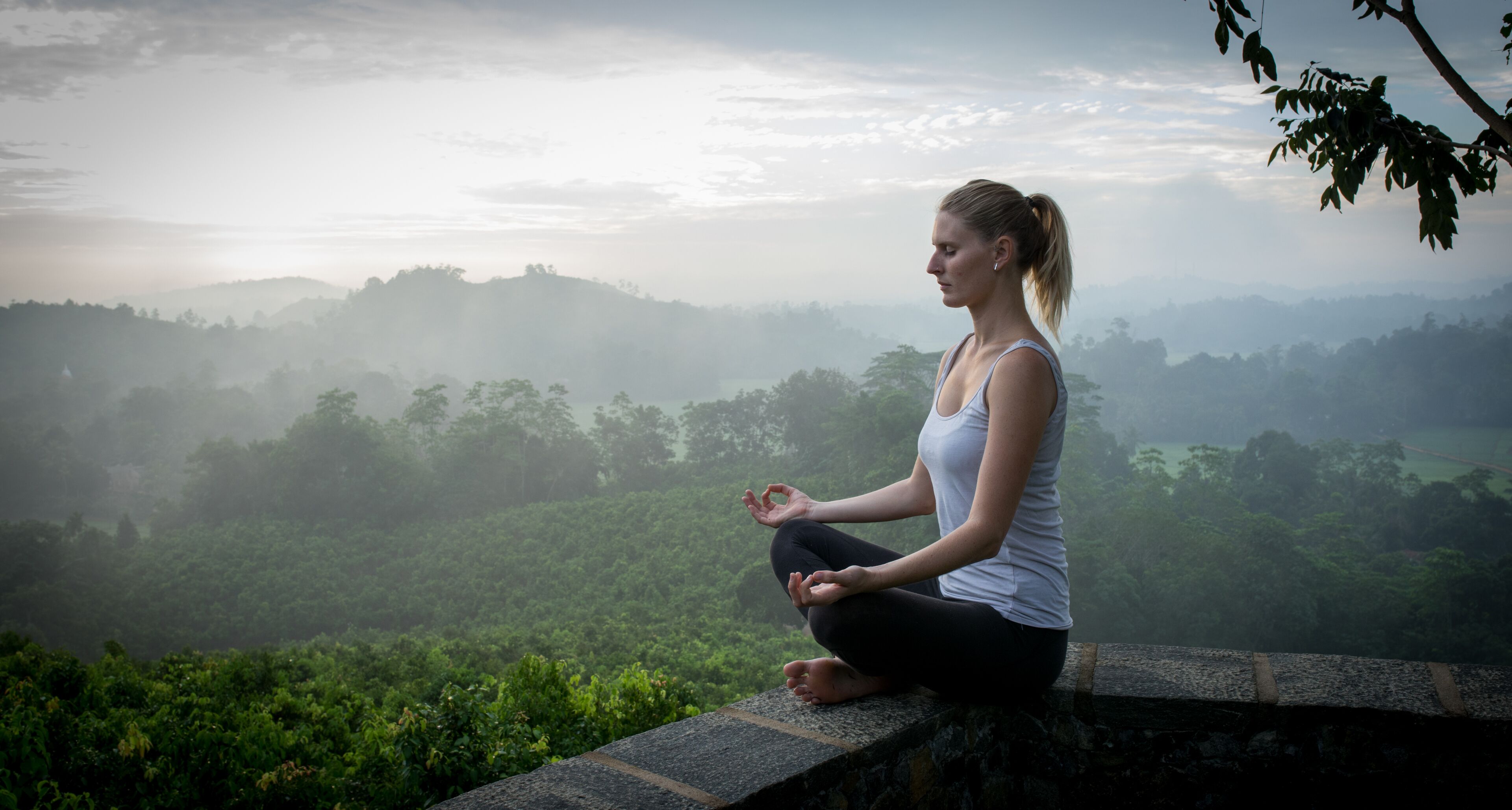 Una persona meditant en un resguard de pedra amb vista a una vall verda.