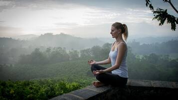 Una persona meditant en un resguard de pedra amb vista a una vall verda.