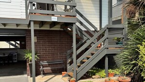 A two-story house with a covered porch, a brick wall, and a staircase leading to the upper floor.