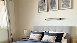 A neatly arranged bedroom with a bed, bedside tables, and framed artwork on the wall.