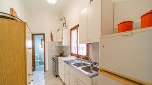 A compact kitchen with white cabinets, a stainless steel sink, and a built-in oven. - Apartment Lo Scoglio in Portoferraio (Portoferraio)
