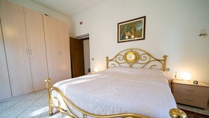 A bedroom with a bed, wardrobe, bedside table, lamp, and a painting on the wall. - Apartment Lo Scoglio in Portoferraio (Portoferraio)