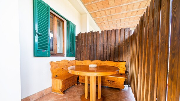 A wooden bench with a round table in front, a window with green shutters, and a wooden fence. - Apartment Lo Scoglio in Portoferraio (Portoferraio)