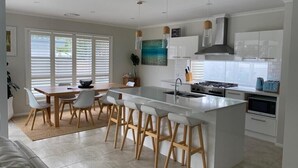 Een moderne keuken met een centraal eiland, witte kasten en een eethoek met een tafel en stoelen.