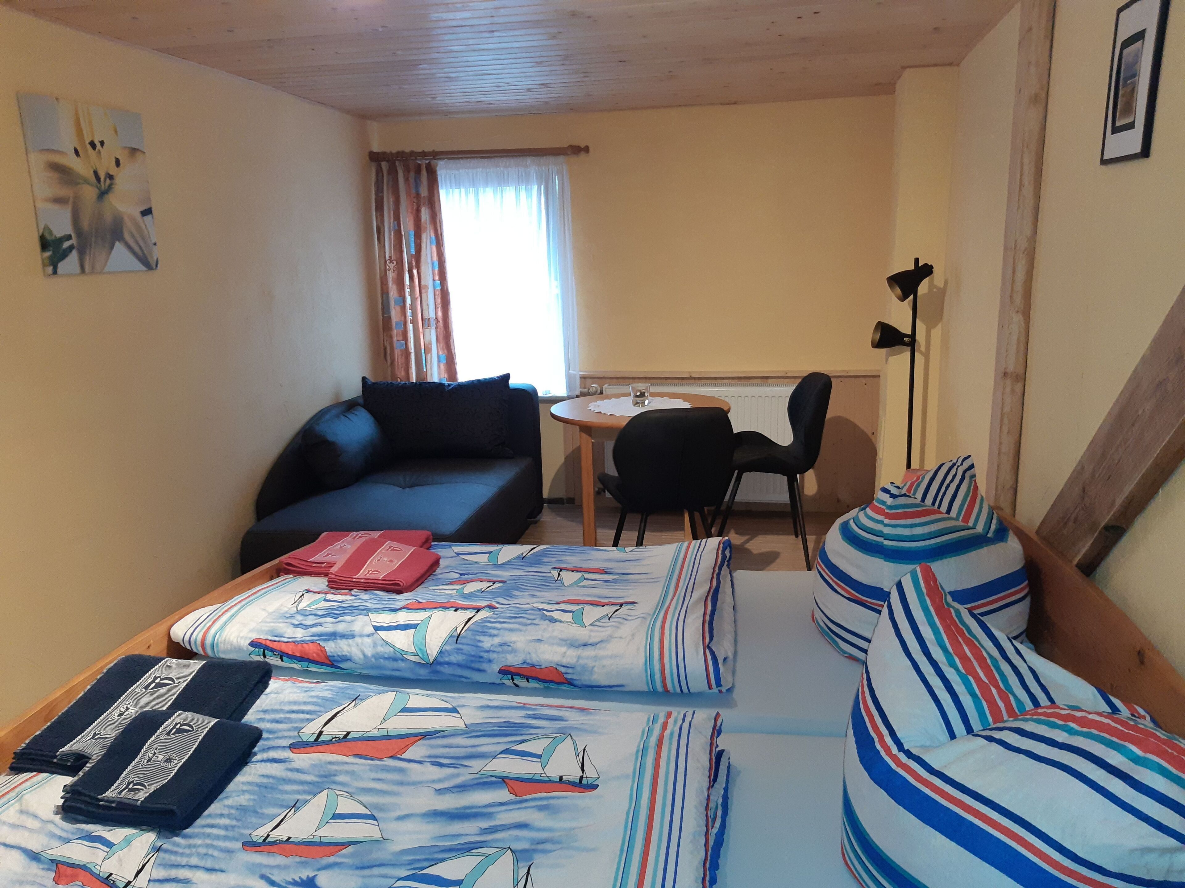 Ett mysigt rum med en säng, en soffa, ett litet bord och en stol.