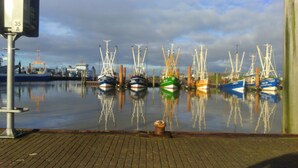 Ein Hafen mit mehreren vertäuten Booten, einem Pflasterweg und einem bewölkten Himmel.