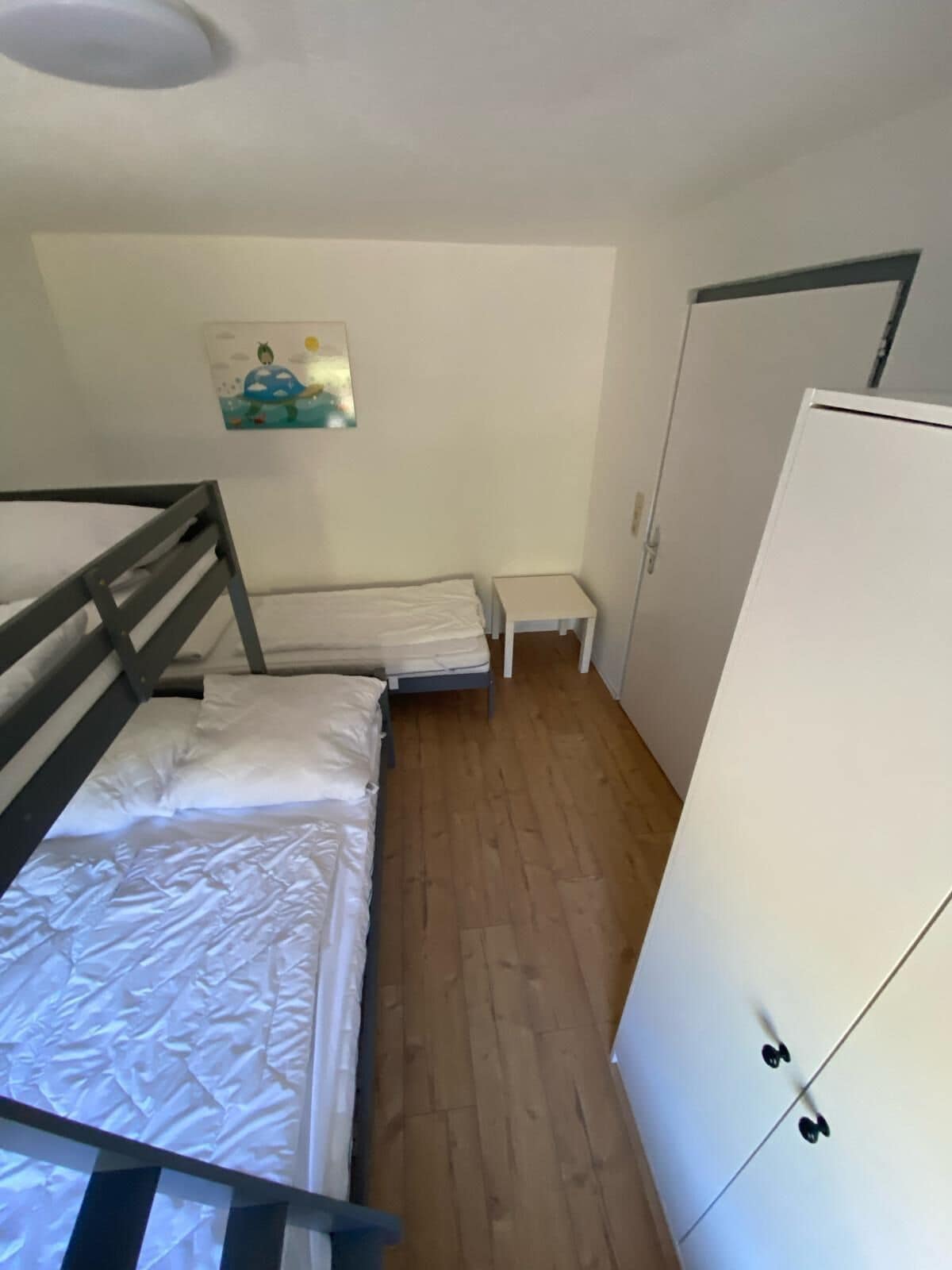 A small, compact room with a bunk bed, a small table, and a wardrobe.