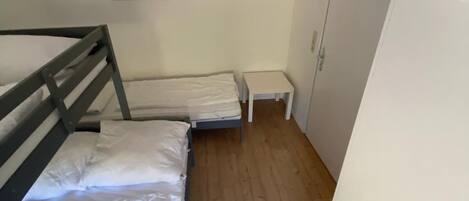 A small, compact room with a bunk bed, a small table, and a wardrobe.
