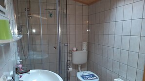 Et badeværelse med hvid vask, toilet og bruser.