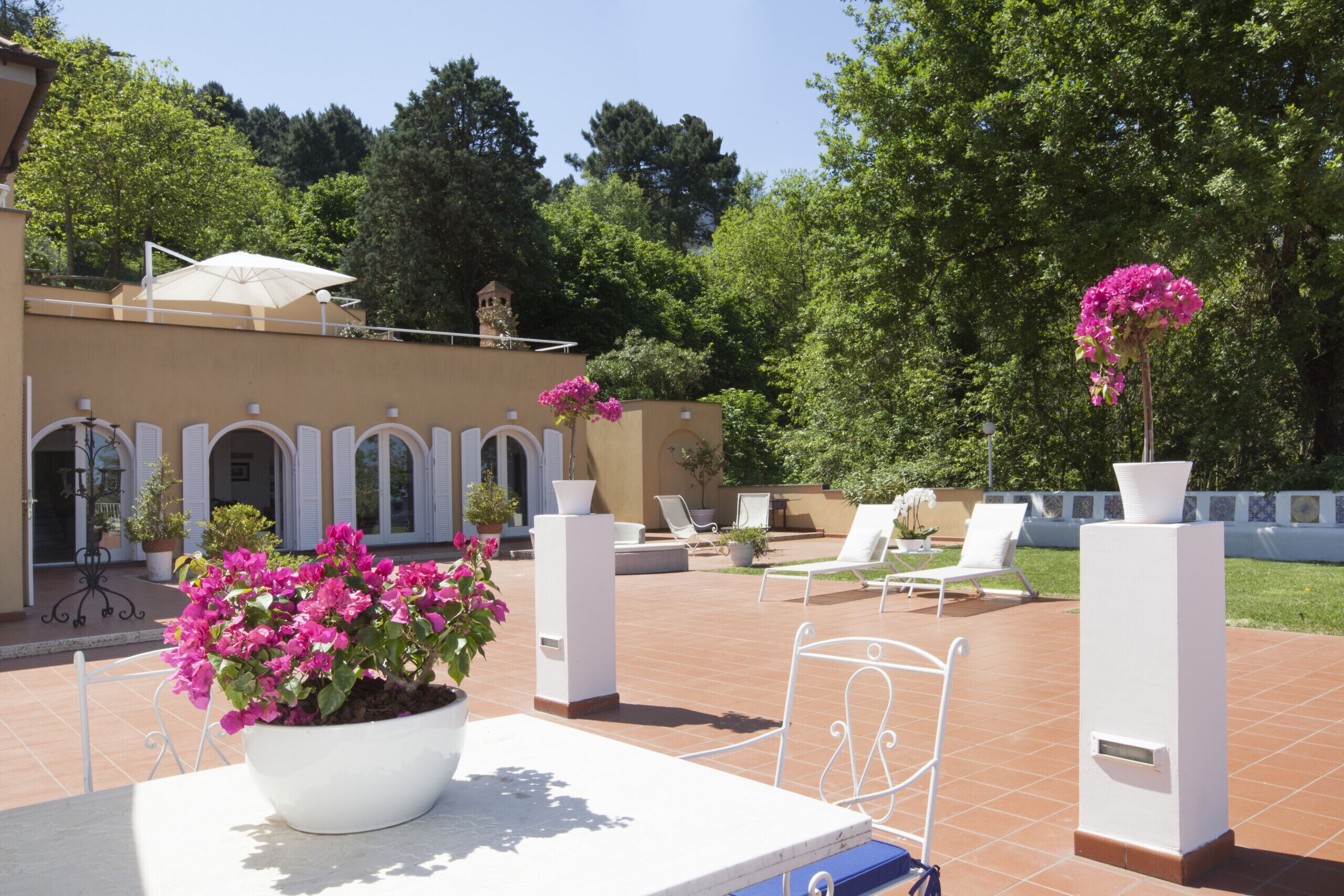 A patio area with a white table, potted plants, and outdoor seating.