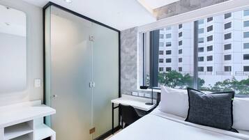 A modern hotel room with a bed, a desk, and a wardrobe.