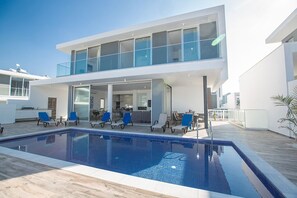 Un bâtiment moderne à deux étages doté d’une piscine, d’un espace extérieur aménagé et d’un balcon.