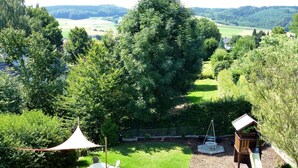 Un jardin avec une table et des chaises de patio, une balançoire et une structure de jeux.