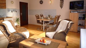 Un salon avec des meubles en osier, une table à manger et un téléviseur.