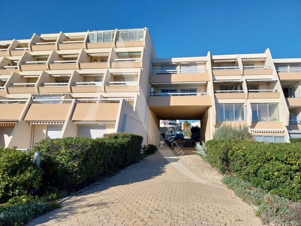 A multi-story building with a central atrium, balconies, and a paved pathway leading to the entrance. - STUDIO AVEC PKG, LES CRIQUES DE LA CORNICHE (Sète)