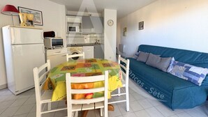 Un espacio habitable compacto con kitchenette, una mesa de comedor con sillas y un sofá azul.