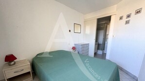 Un dormitorio con cama, mesita de noche, lámpara, cómoda y puerta que da a un baño.