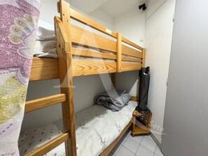 Cozy single-room accommodation with a wooden bunk bed and a heater for a comfortable stay.