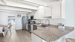 A modern kitchen with white cabinetry, granite countertops, and stainless steel appliances. - Ocean Colony 8 by Seaside Vacations & Sales (Ocean City)