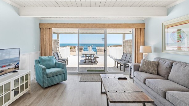 A living room with a view of the beach, a sofa, a TV, and a coffee table. - Ocean Colony 8 by Seaside Vacations & Sales (Ocean City)