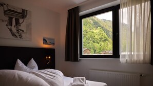 A hotel room with a bed, a window with curtains, a radiator, and a painting on the wall. - 4802 Cirrus 2 (St. Gallenkirch)